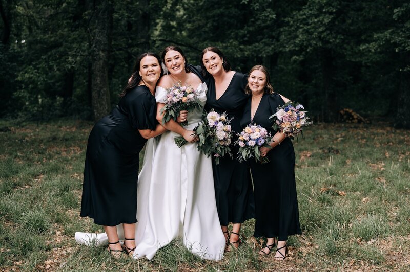 bridesmaids in ruby kendall black dresses with bride at forest at bangor farm darfield