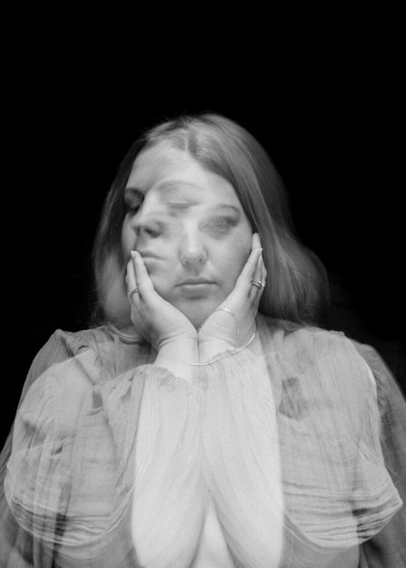 black and white image double exposed of woman holding face