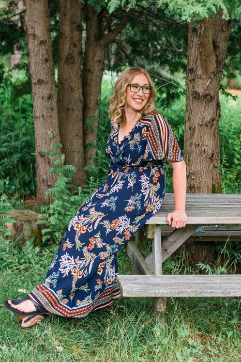 A woman in a floral dress sits on a bench, reflecting a serene moment in Ontario, Canada, as a therapist.