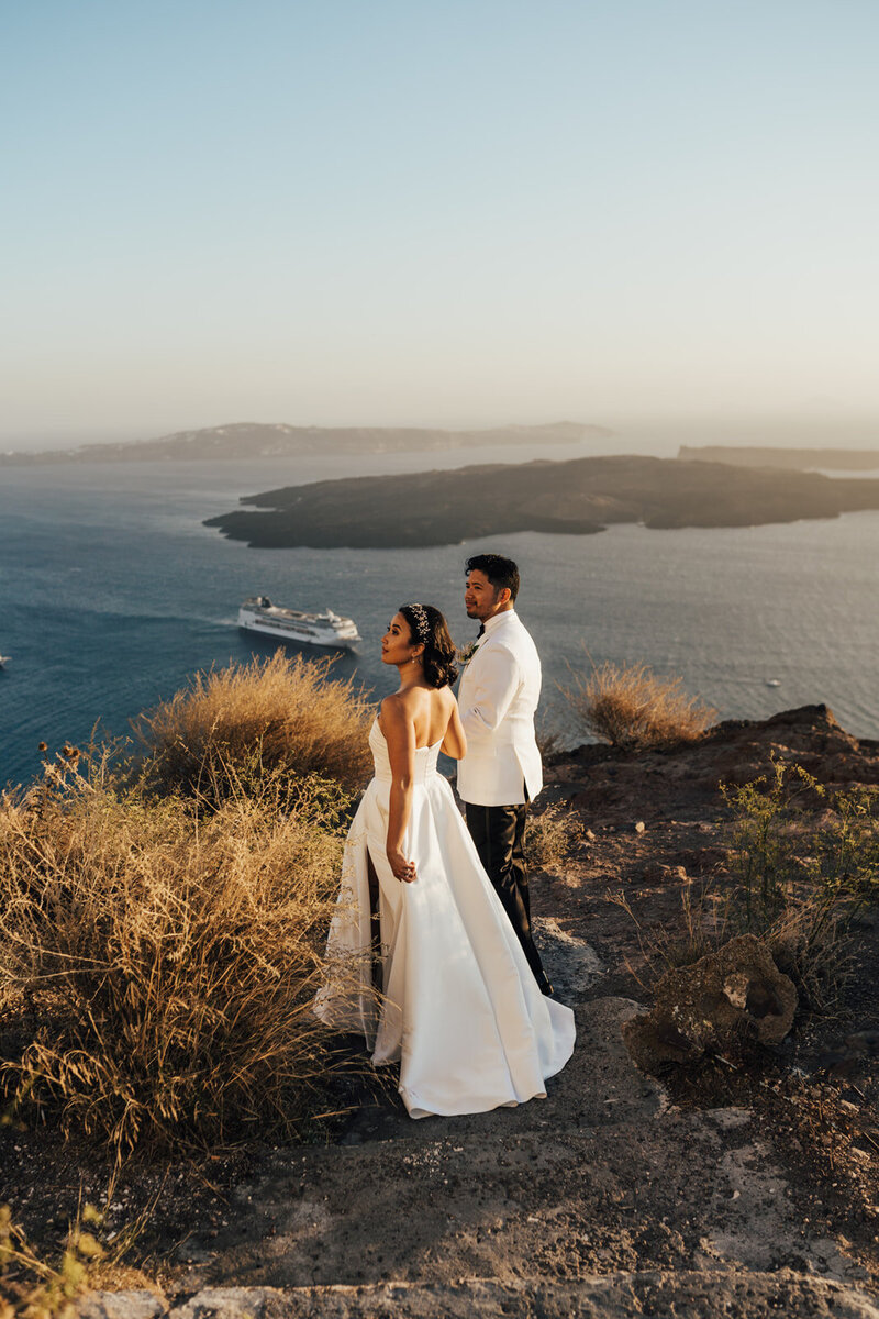 Bride and groom walking on cliffs of santorini