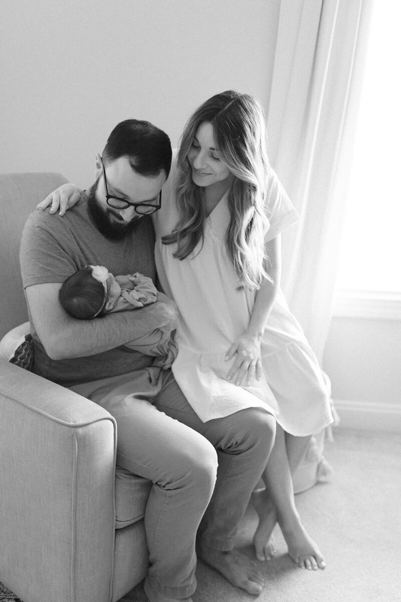 Mom and dad on rocking chair with newborn baby girl