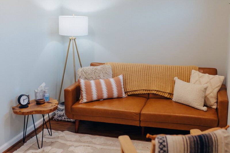 orange couch with pillows and a lamp next to it