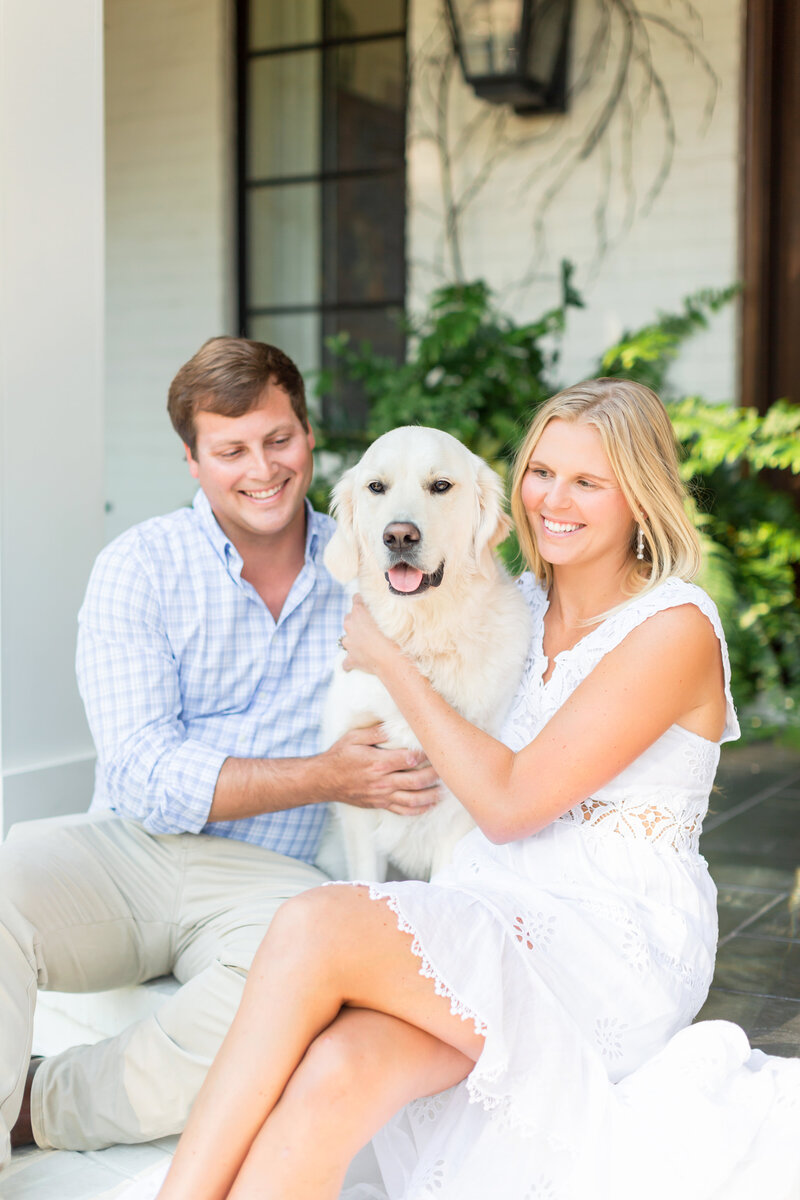A joyful couple in soft, natural light, smiling as they pose with their golden retriever, embodying love and companionship