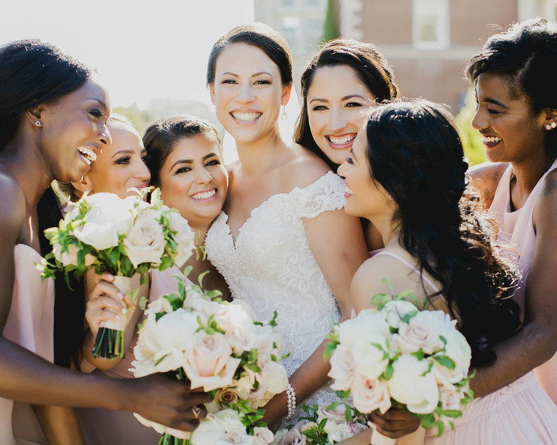 Bridesmaids gather around Bride as they all laugh and smile