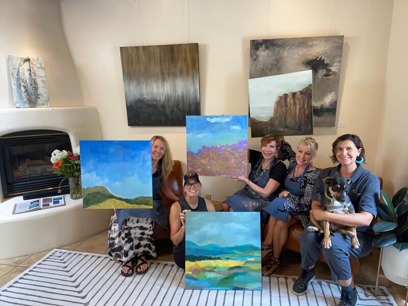 group of women smiling and holding paintings they painted