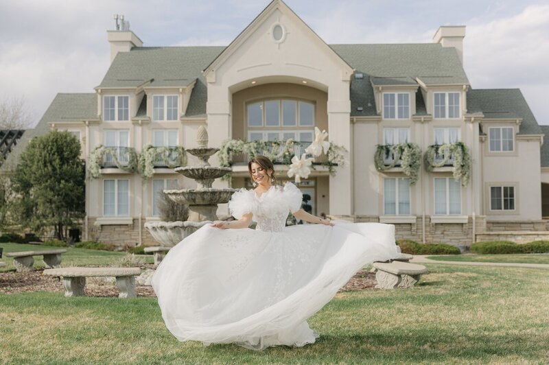 Whimsical portrait of bride twirling in her designer gown on the lawn of the chateaux at fox meadows luxury wedding venue in Denver, Colorado 