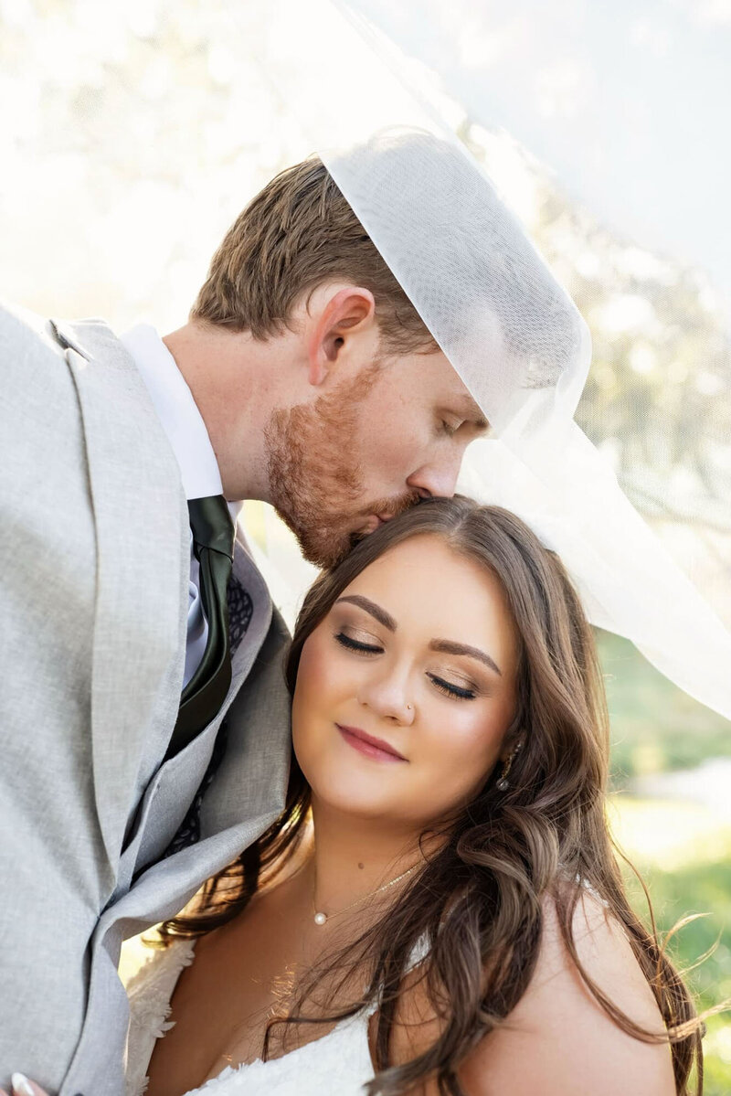 Groom kissing bride forehead at Raleigh Wedding
