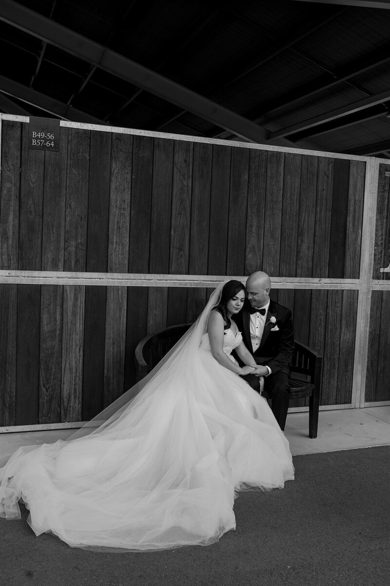 Couple sitting on a bench. The brides dress is spread out behind her