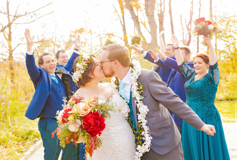 A wedding party celebrates the bride and groom with Gramercy Mansion Wedding Photographer in the gardens.