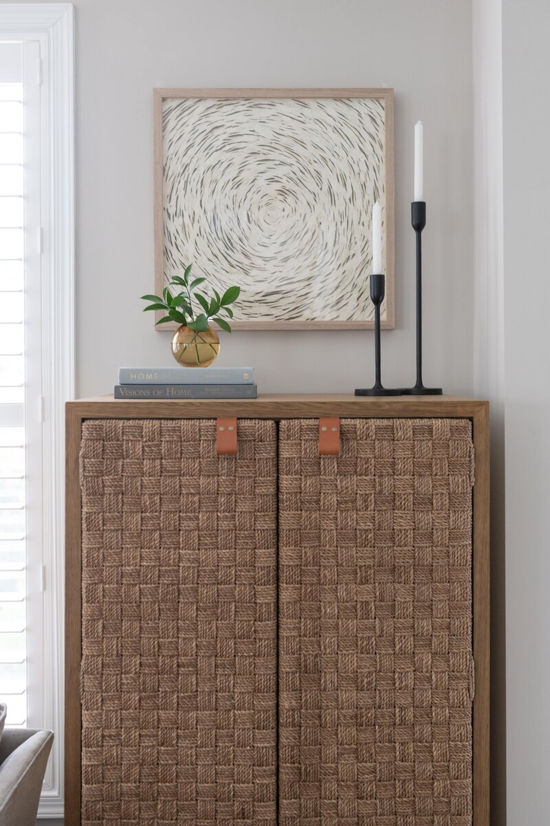 Detail of a project designed by Glass House Design Group in Boston. Sideboard with leather handles, books and black candle holders with an abstract painting. Effortlessly chic New England interior design that works for real life.