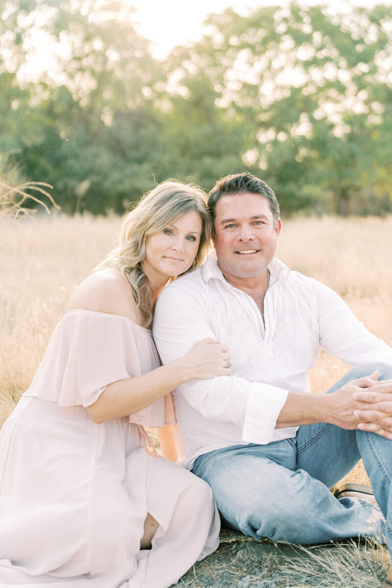 Fresno Maternity Newborn Photographer, About Me Page, Pictured with husband, in a grassy field.