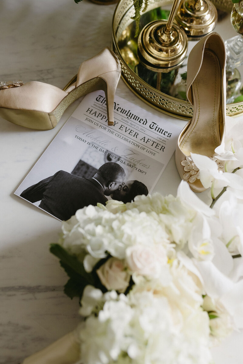 Detail overhead shot of the bride's newspaper invitation,flowers and bridal heels