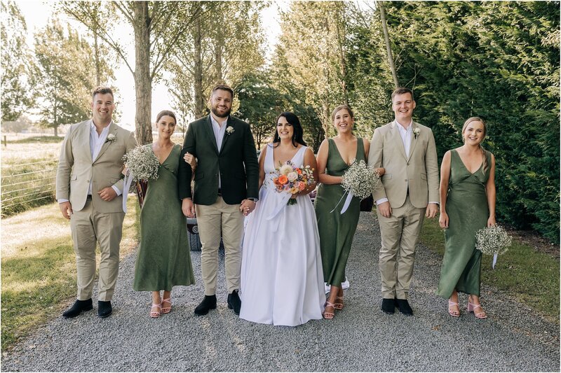 bridal party girls in green dresses from showpo boys in sand and olive on road sunny day christchurch