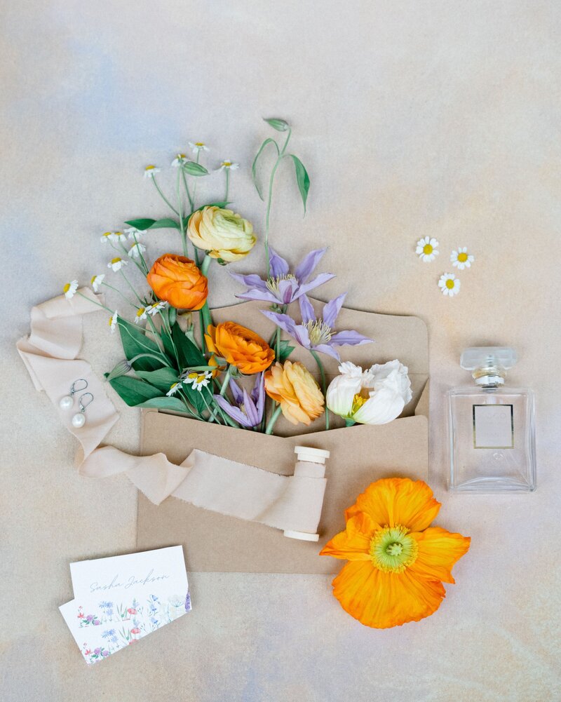 Flatlay of invite details with flowers mixed all in.