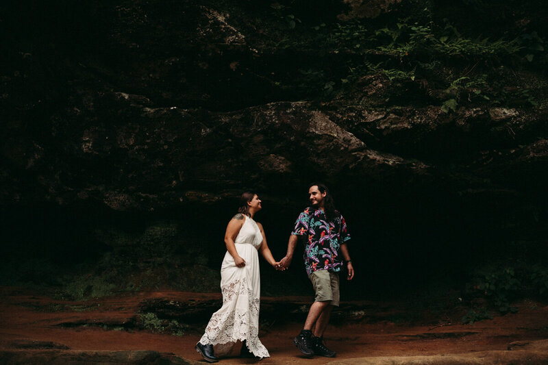 Couple walk against cave walls at Old Mans Cave for their elopement