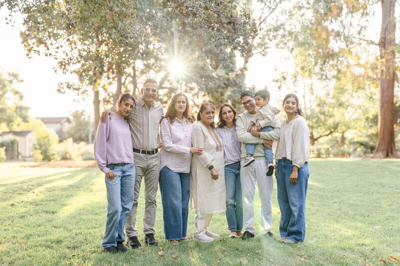 Extended family smiling at camera during fall golden hour portrait session in garden setting