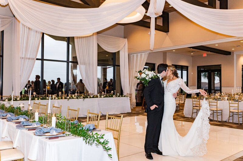 Bride and Groom share kiss together in the wedding reception space before being joined by their guests