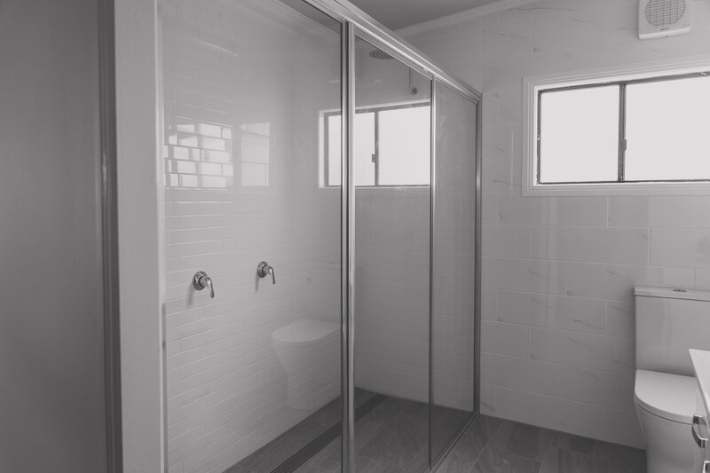 Sleek bathroom featuring a custom glass pivot shower door, blending functionality and modern style.