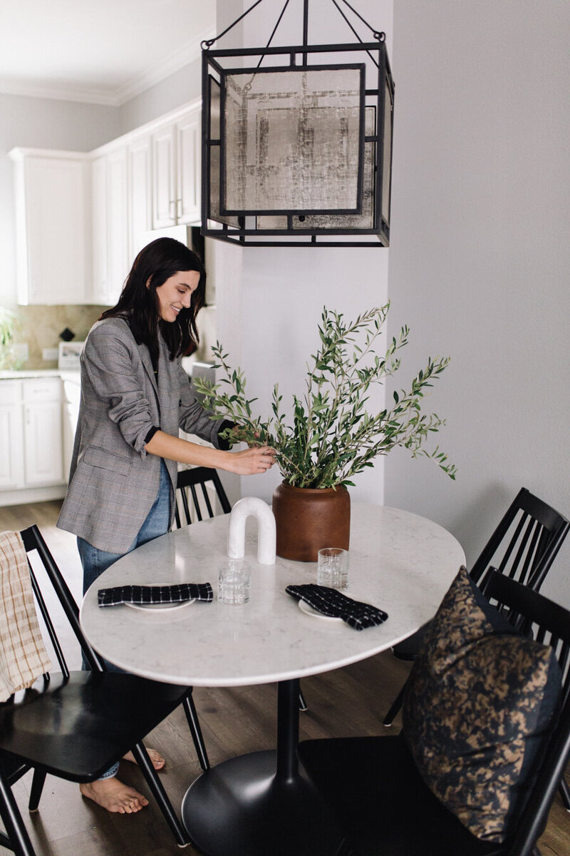 Hope Danyla decorating a table in an Art-forward, masculine dining room, designed by Hope Miriam Designs in DFW