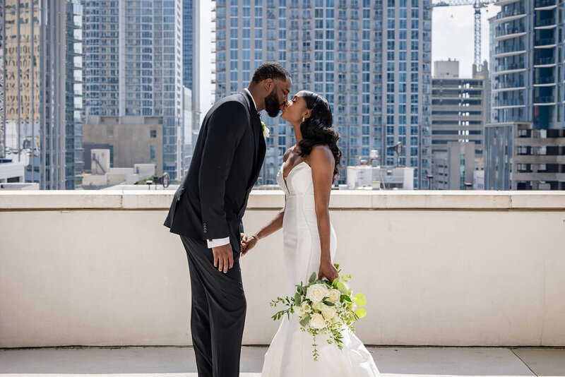 a bride and groom kiss on a rooftop in charlotte