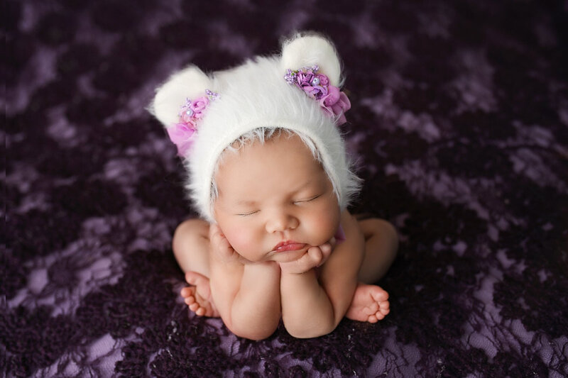 Sleeping infant on purple blanket in frog position