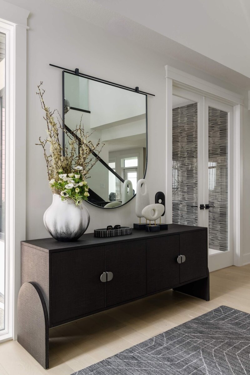 A modern foyer with an arched detail cabinet and oversized mirror. 