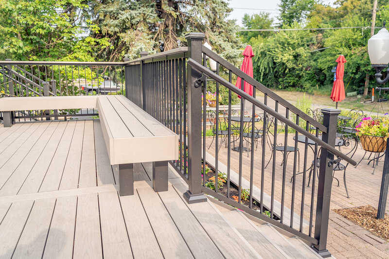 Built-in deck bench next to stairway leading down to ground level, all built using composite decking materials. 