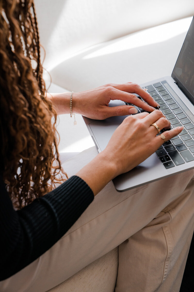A woman's hands typing on a laptop