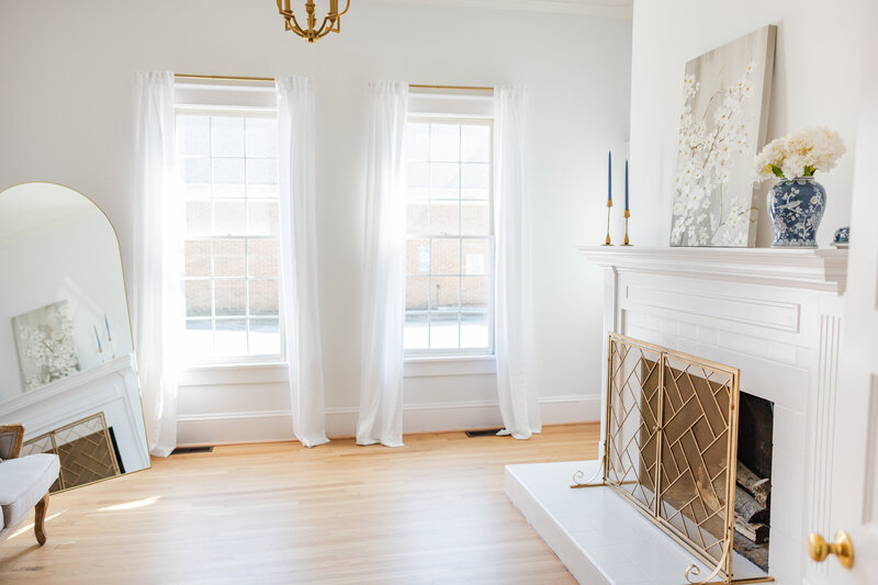 a white fireplace in a room with bright natural light