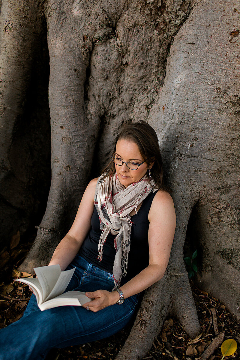 Image of Emily May reading a book under a tree
