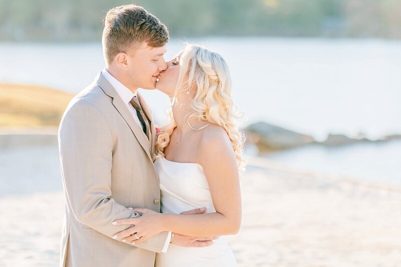 Bride and groom kiss on Lake Martin beach | New Water Farms Wedding Photography
