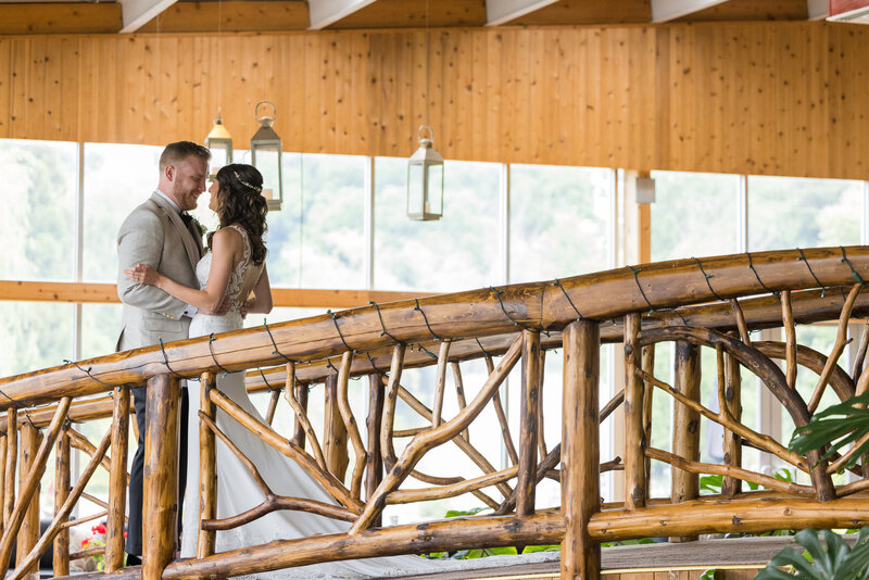 Bride and groom sharing a private moment on a rustic wooden bridge during their wedding day.