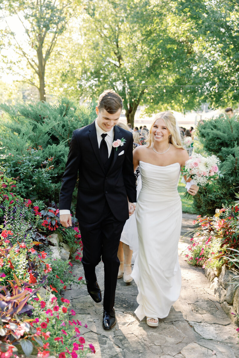 Bride and groom excitedly walk to reception after their ceremony outside. Taken by Lacey Graham Illinois wedding Photographer