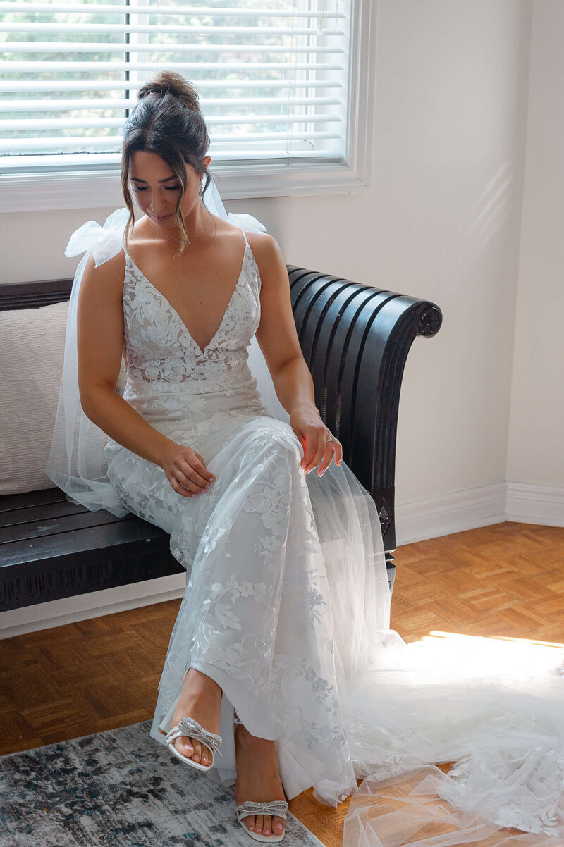 Ottawa wedding photography of a bride sitting on a bench to put her shoes on
