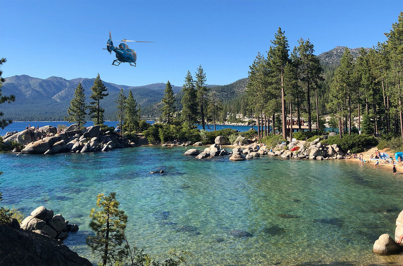 airbus ec130 b4 blue helicopter flying above lake tahoe for tour