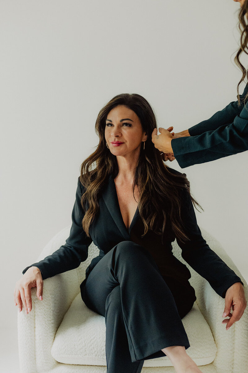 a woman doing a client's hair during a portrait photo session