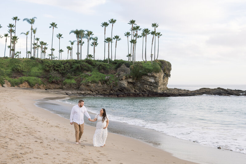 maternity photo on the beach with cliffs and palm trees