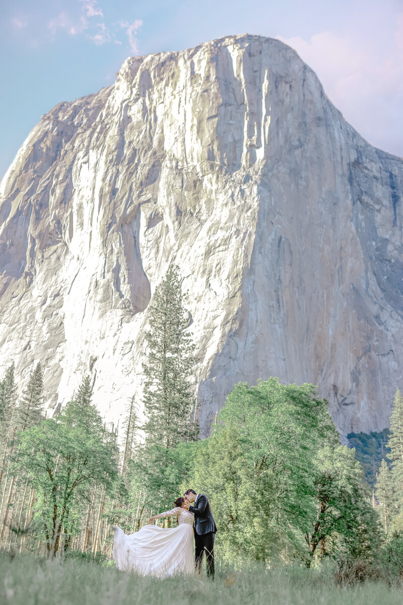 Bride and groom sharing a romantic kiss with El Capitan towering in the background at Yosemite National Park, capturing a timeless and adventurous love story.