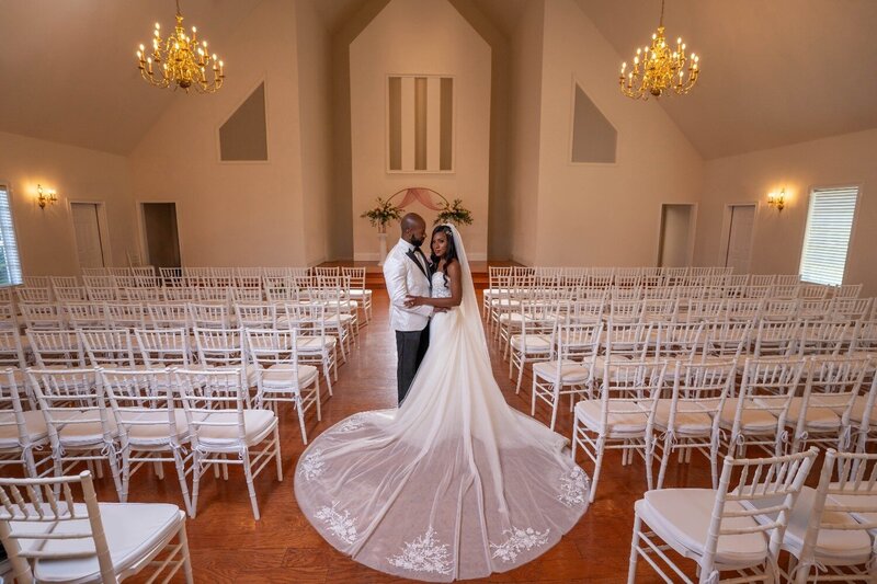 Bride and groom stand in an empty chapel, showcasing her long dramatic train