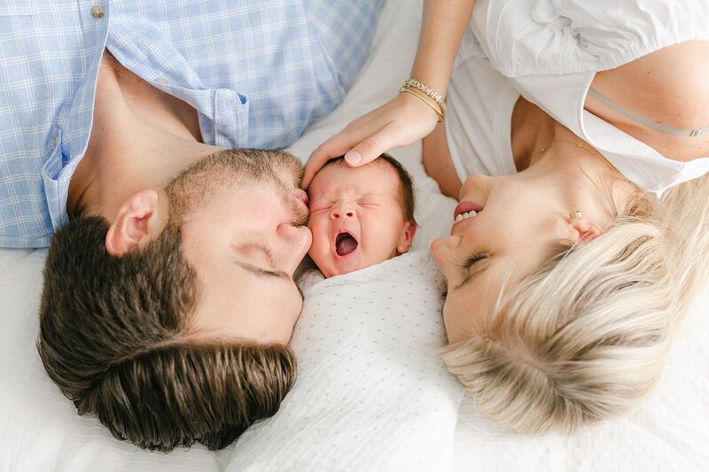 Newborn baby yawning laying with mom and dad