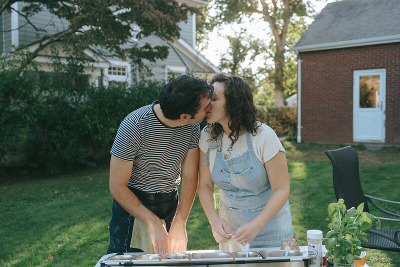 couple kissing while making pizza during engagement photos, captured by Elsie Goodman, an NYC engagement and couples photographer