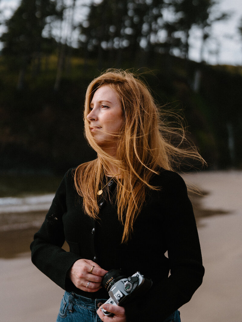 Jaime is an Oregon wedding photographer. She's sitting and smiling with her camera. 