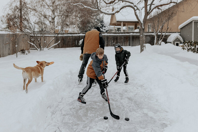 Dad and two young boys playing ice hockey