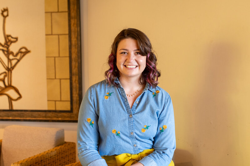 Smiling woman sitting in a modern indoor space, photographed by Vyrl Photo, showcasing Tucson brand photography.