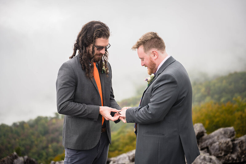 A queer couple exchanges rings atop a rocky mountain on their elopement day at Shenandoah National Park.