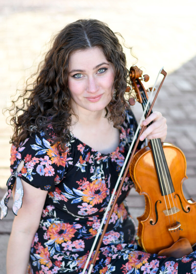 Violinist Erika Burns sits down holding her violin.