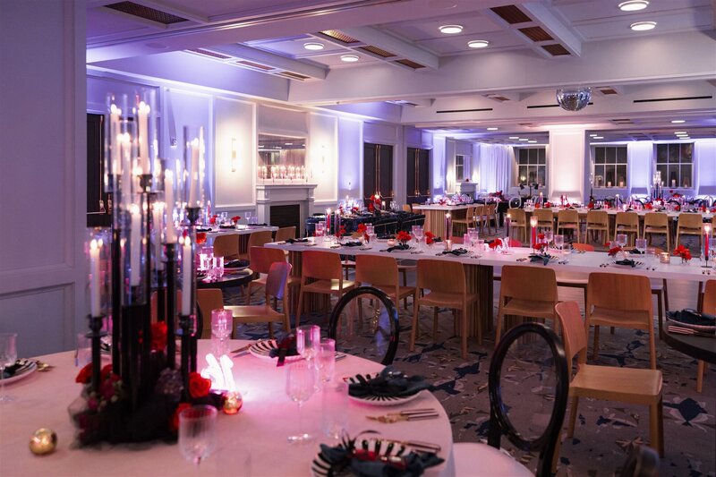 Modern gothic reception room with white and black tables, red florals pops, and gothic candelabras in the ballroom at the Line Hotel DC