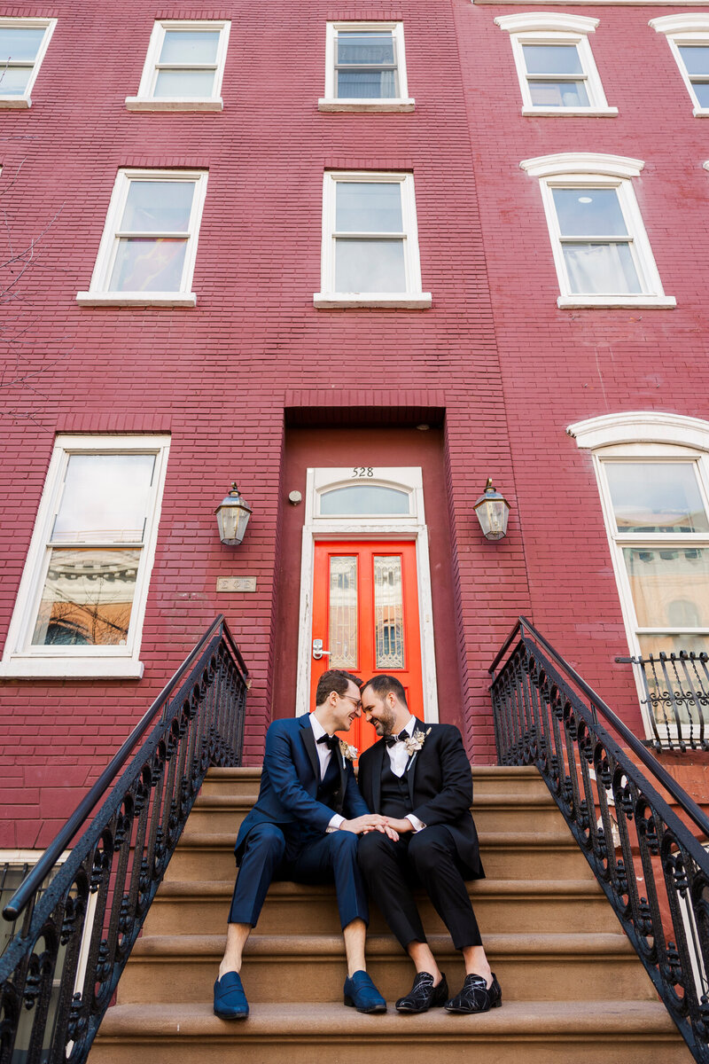 Two grooms sitting on brownstone steps after their LGBTQ wedding in Hoboken, NJ