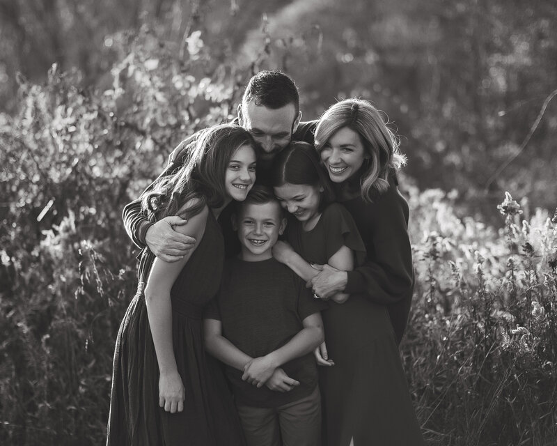 Family hugs each other for their family picture  in black and white family portrait.