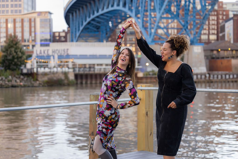 Women dancing with blue bridge in background